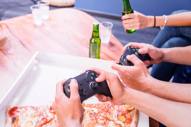 Amici che mangiano pizza e giocano sulla console