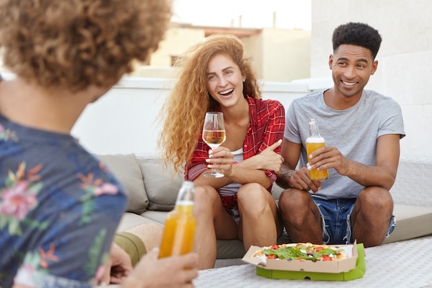 Amici che mangiano pizza gustosa e si divertono chiacchierando