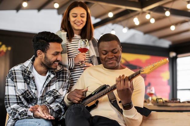 Amici che si divertono mentre ascoltano il loro amico suonare la chitarra