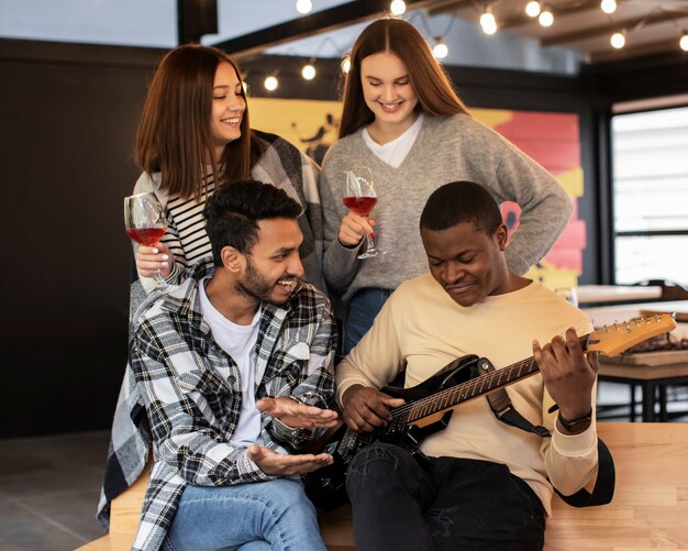 Amici che sorridono mentre ascoltano il loro amico suonare la chitarra