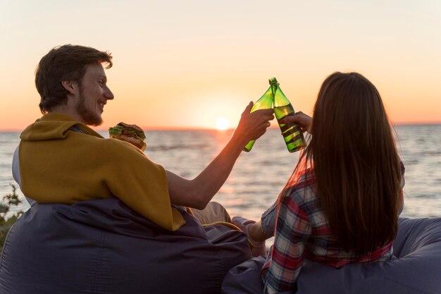 Amici che tostano con birra all'aperto al tramonto