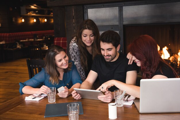 Amici che utilizzano tavoletta digitale in bar