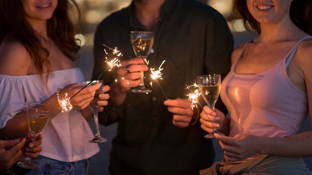 Amici del primo piano che posano con i fuochi d'artificio