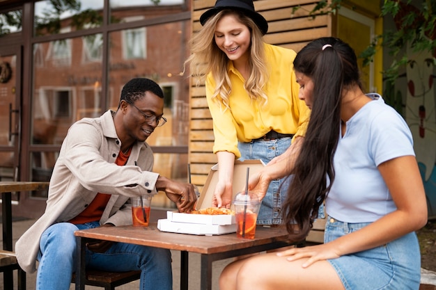 Amici del tiro medio che mangiano pizza all'aperto