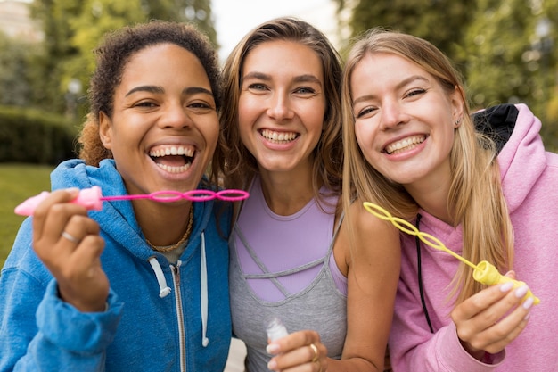 Amici delle donne di vista frontale che fanno le bolle di sapone