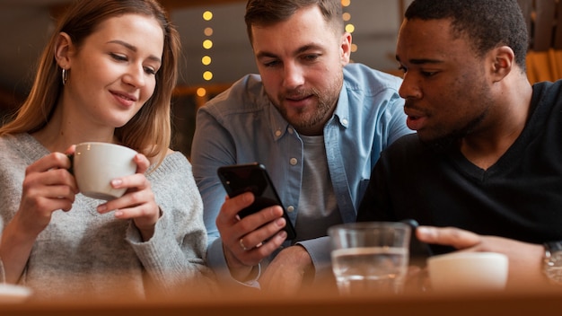 Amici di angolo basso che guardano sul cellulare