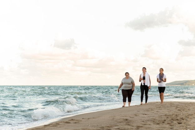 Amici di fitness di tiro lungo che camminano sulla riva