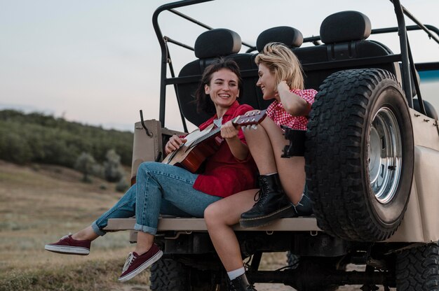 Amici di sesso femminile a suonare la chitarra mentre si viaggia in auto