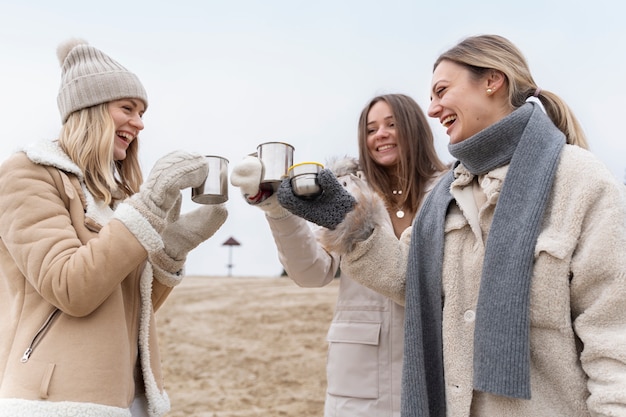 Amici di sesso femminile che bevono acqua sulla spiaggia durante il viaggio