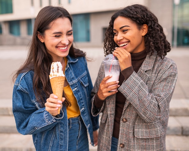 Amici di smiley che mangiano gelato e frappè all'esterno