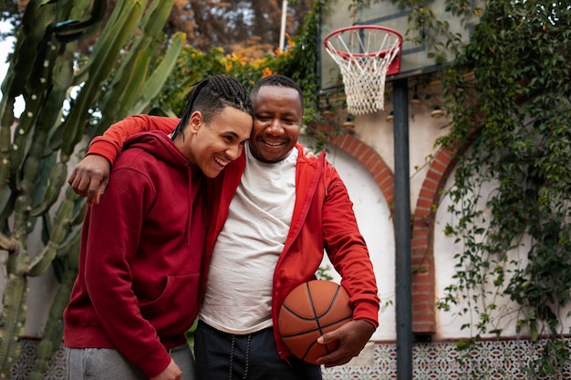 Amici di tiro medio che giocano a basket all'aperto