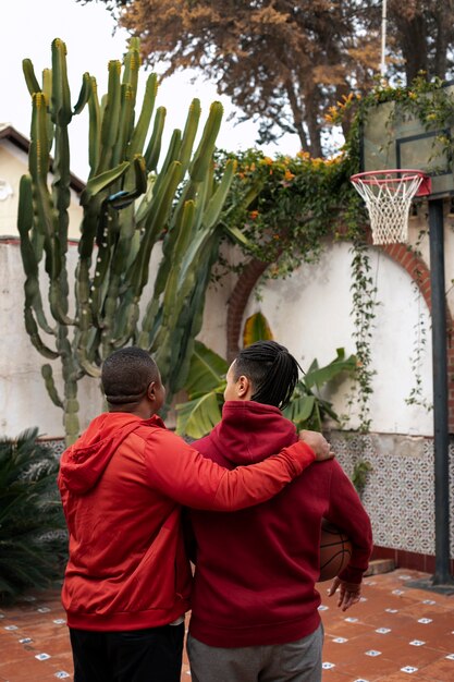 Amici di tiro medio che giocano a basket all'aperto