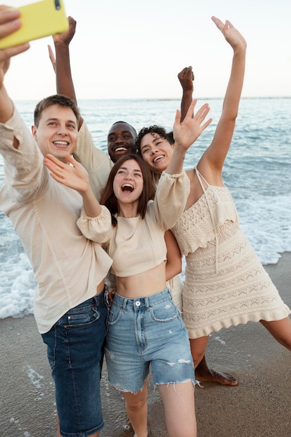 Amici di tiro medio che si fanno selfie sulla spiaggia