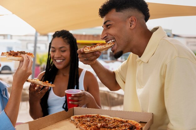 Amici di vista laterale che mangiano pizza