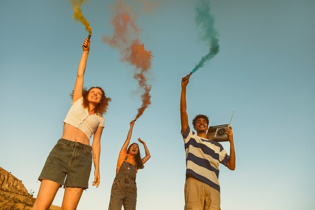 Amici felici ad angolo basso con fumo colorato