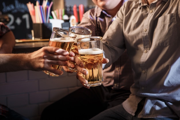 Amici felici che bevono birra al bancone in pub