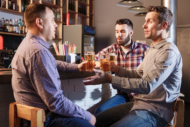 Amici felici che bevono birra al bancone in pub