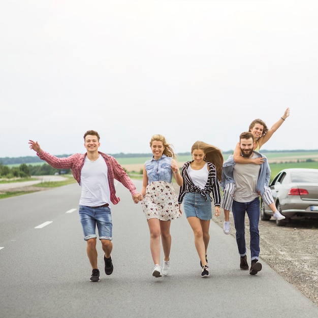 Amici felici che camminano sulla strada insieme rendendo divertente