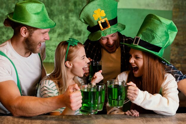 Amici felici che celebrano insieme st. patrick's day con drink al bar