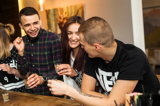 Amici felici che godono bevendo tequila al bar