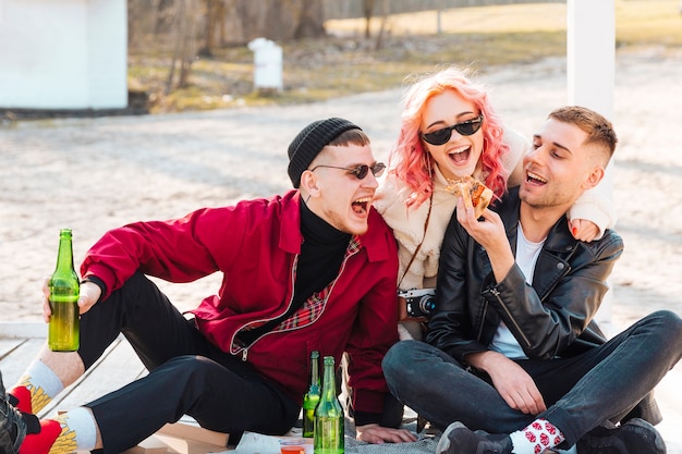 Amici felici che mangiano e bevono insieme facendo festa