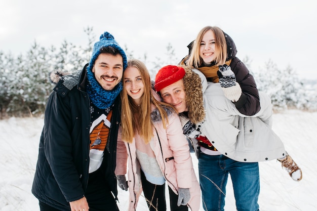 Amici felici che stanno nella foresta di inverno