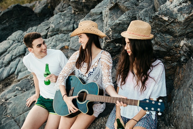 Amici felici in spiaggia con la chitarra