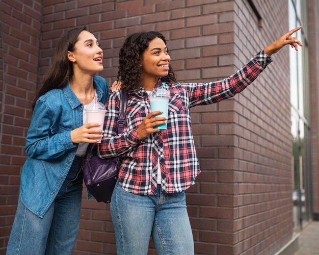 Amici femminili all'aperto che mangiano frappè