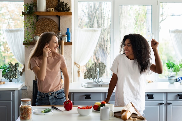 Amici femminili che ballano e si divertono in cucina