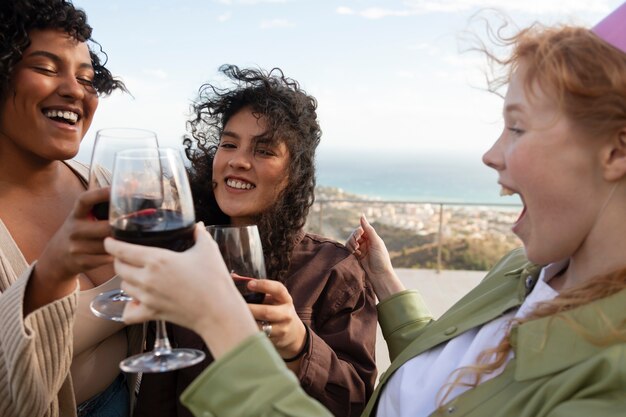 Amici femminili che brindano con bicchieri di vino durante la festa all'aperto