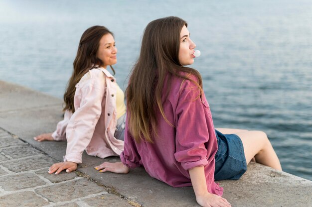 Amici femminili che riposa in riva al lago