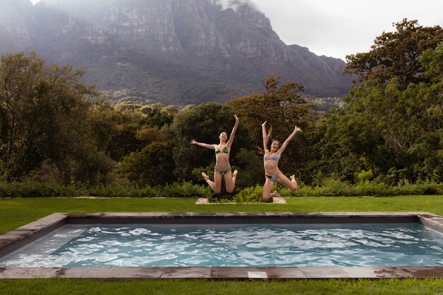 Amici femminili che saltano nella piscina al cortile