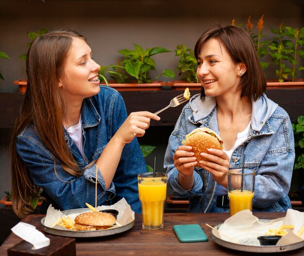 Amici femminili che si alimentano reciprocamente hamburger