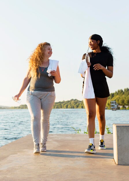 Amici femminili che si esercitano insieme in riva al lago