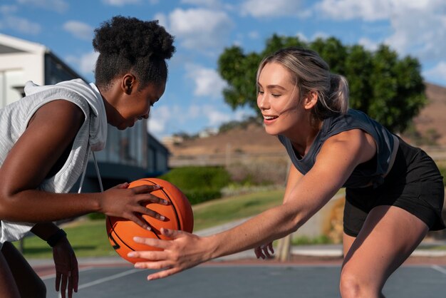 Amici femminili di vista laterale che giocano a basket