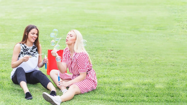 Amici femminili felici che godono del salto delle bolle nel parco