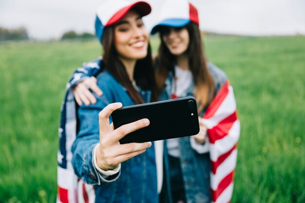 Amici femminili in berretti colorati prendendo selfie