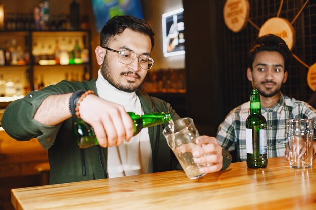 Amici indiani in un pub. Ragazzi e ragazza al bar. Celebrazione davanti a un boccale di birra.