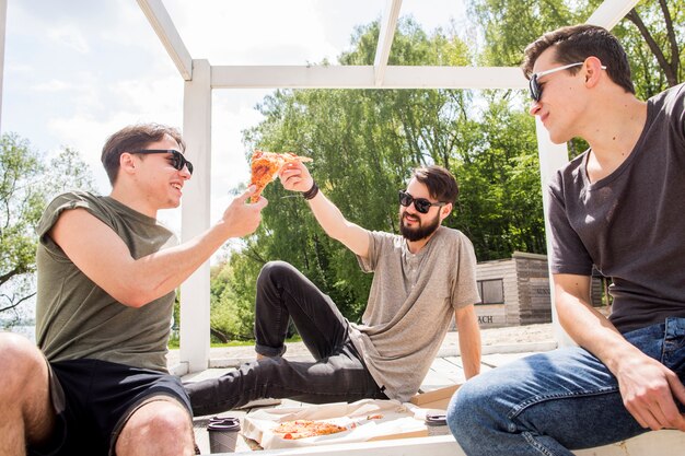 Amici maschii che dividono la pizza