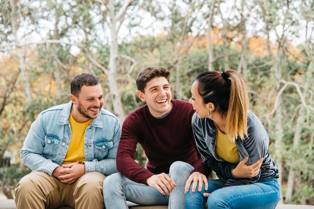 Amici multietnici che raccontano storie divertenti e seduti nel parco