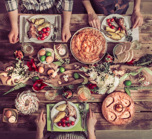 Amici o famiglia in vacanza a tavola con carne di coniglio, verdure, torte, uova, vista dall'alto.