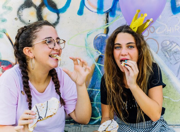 Amici seduti con palloncini e torta di compleanno