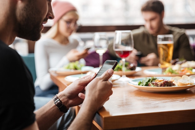 Amici seduti in un caffè e utilizzando i telefoni cellulari