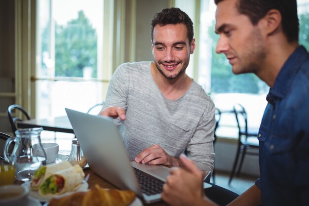 Amici seduto al tavolo e con laptop in caffetteria ©