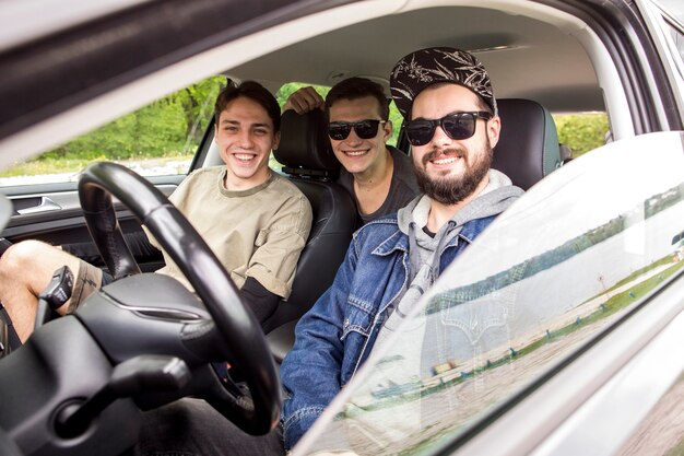 Amici sorridenti che si siedono in macchina nel viaggio