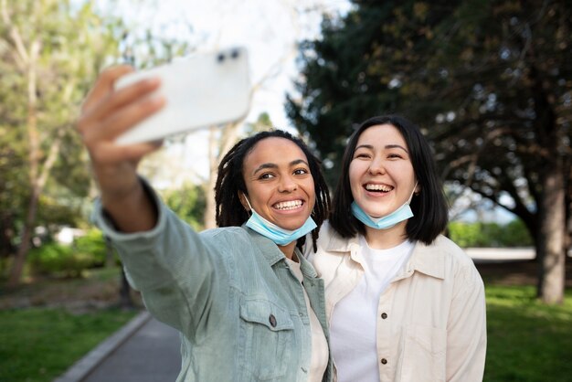 Amici sorridenti del colpo medio che prendono selfie nel parco