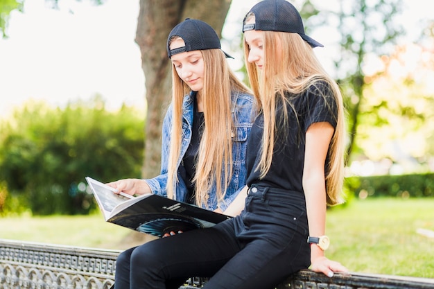 Amici teenager femminili che leggono libro sulla rete fissa