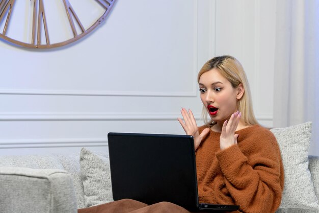 Amore virtuale carina giovane ragazza bionda in maglione accogliente alla data di distanza del computer scioccata