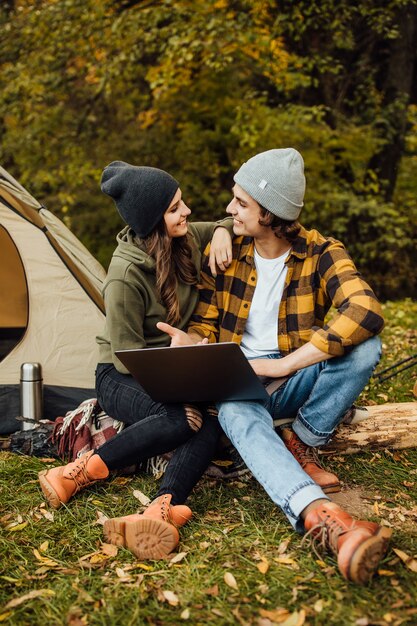 Amorevole coppia di giovani freelance guarda film nella foresta vicino alla tenda