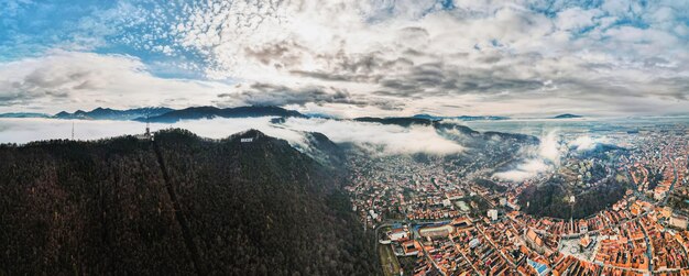 Ampia vista aerea del drone di Brasov in inverno Romania Edifici residenziali montagne nuvole basse